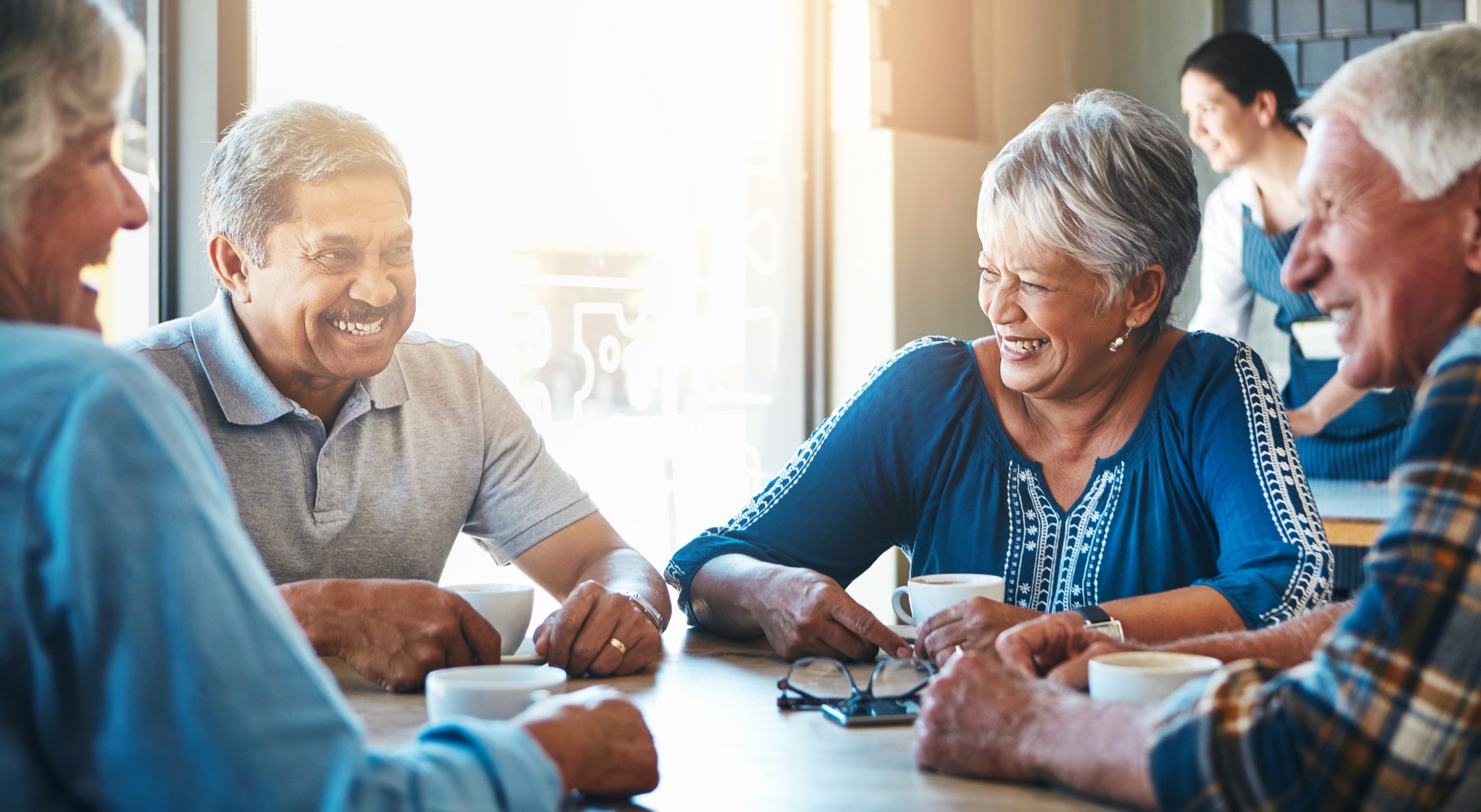 Elderly, people and group on holiday at cafe to relax on vacation in retirement. Senior, friends and laughing at coffee shop to drink latte, espresso and funny chat in city or morning with tea